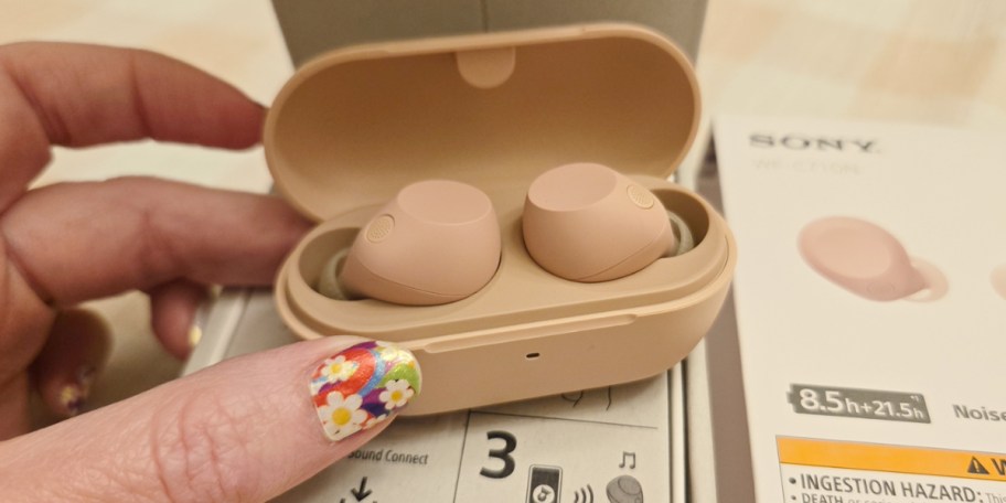 hand holding pink headphones in case 