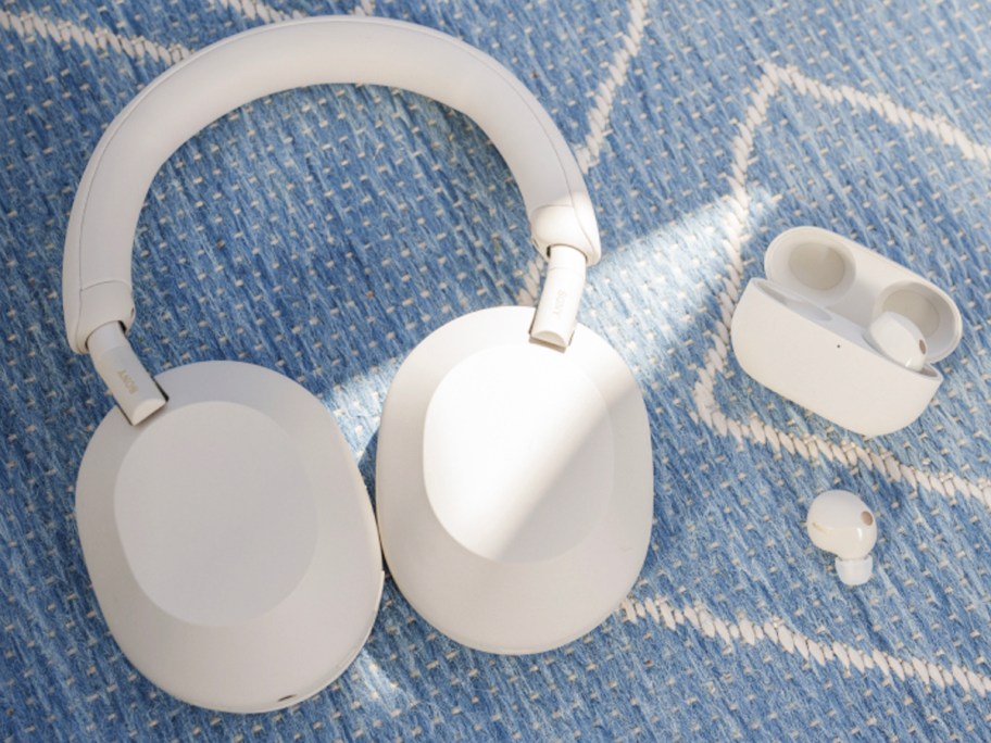white over ear headphones and earbuds with case on blanket 