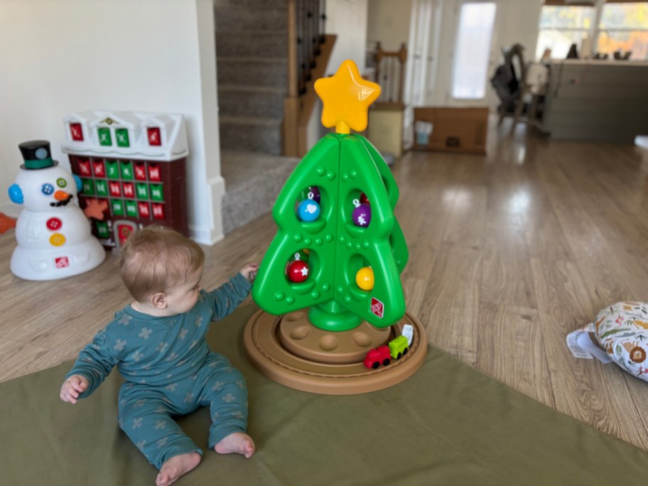 baby sitting next to a step2 christmas tree