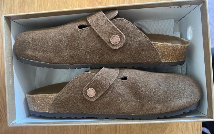 a pair of tan suede clogs in a box