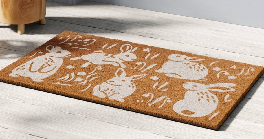 a coir doormat with white bunny designs on it by a door