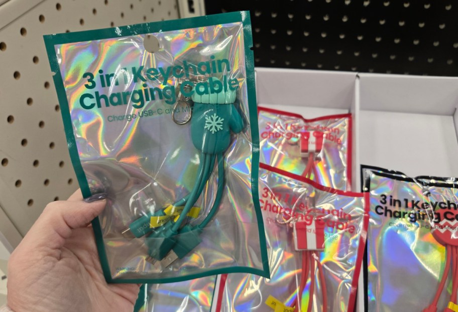 A hand holding up a green mitten holiday keychain cable.