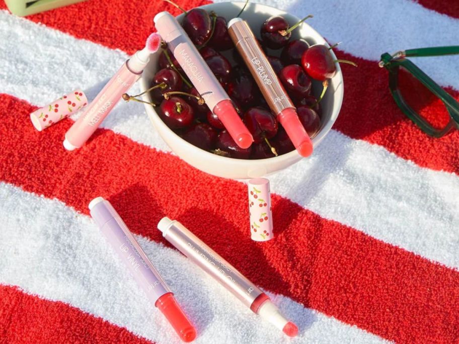 A bowl of cherries with a tarte maracuja juicy lip glosses and oils