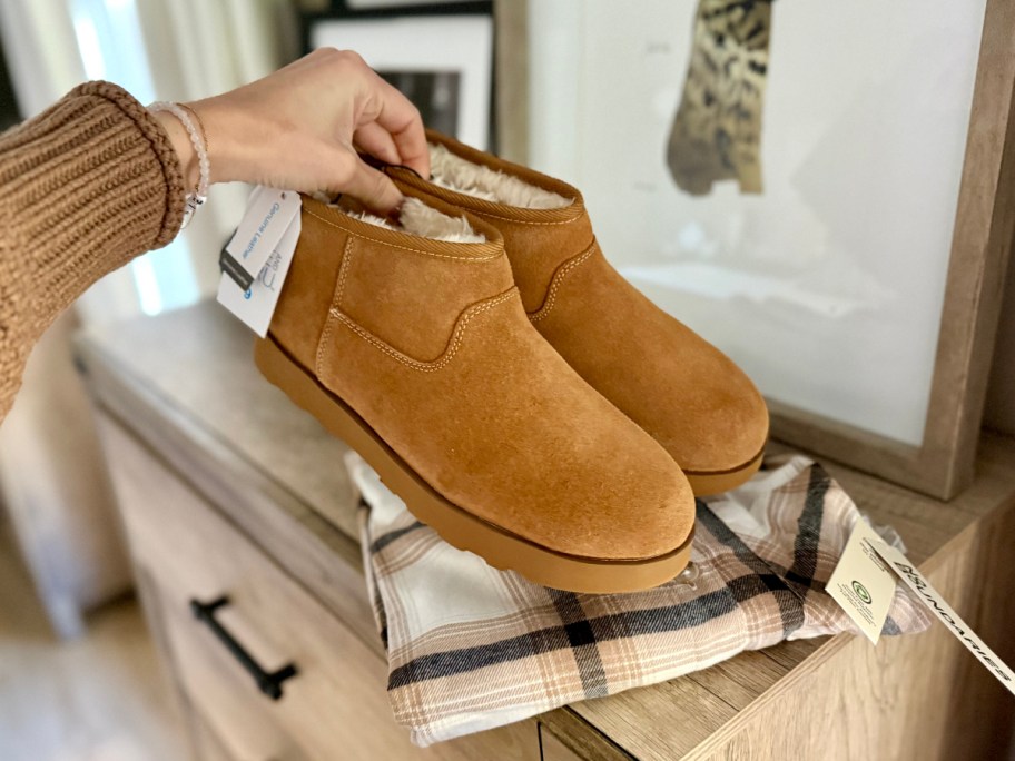 holding a pair of chestnut-colored suede boots