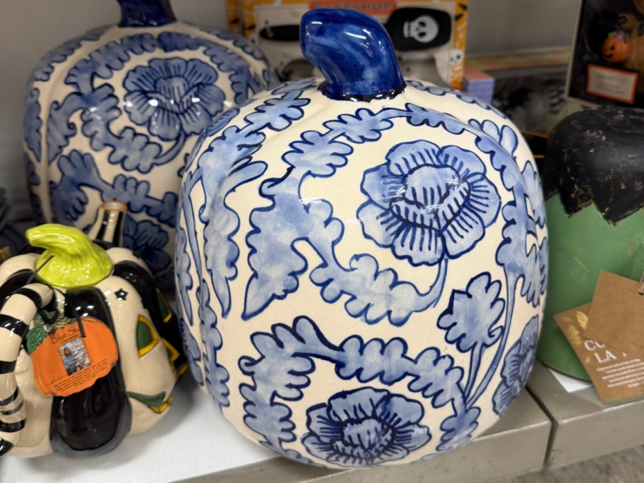A ceramic pumpkin with a blue and white floral and leaf pattern and a solid blue stem.