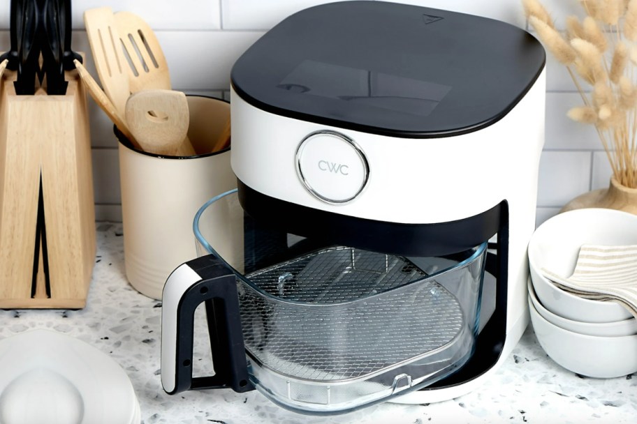 white air fryer with glass basket next to cooking utensils jar