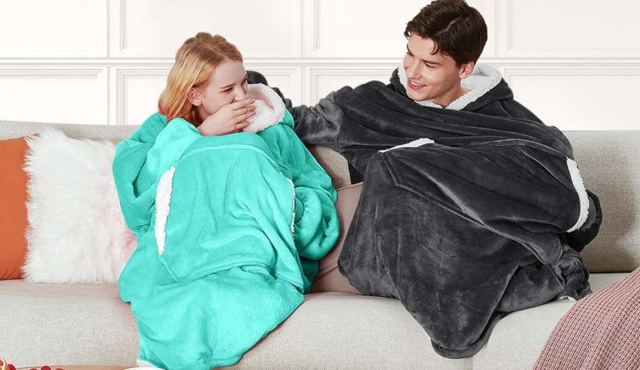 two people on a couch wearing Wearable blanket hoodies