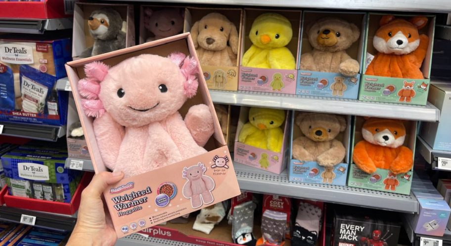 A hand holding an axolotl weighted warmer plush.