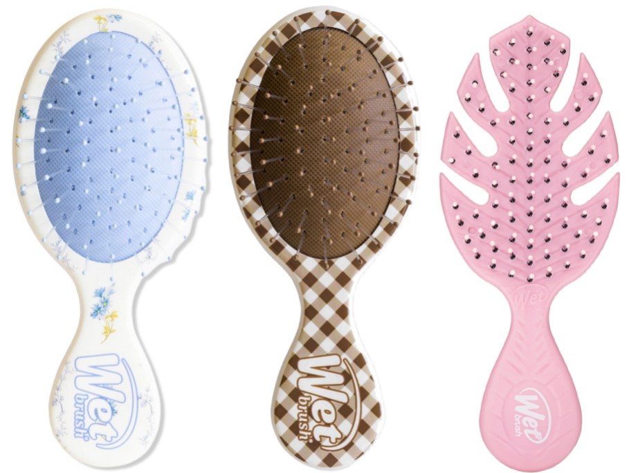 Three Wet Brush hairbrushes featuring a light blue floral design, a brown and white checkered pattern, and a pink leaf-shaped design.
