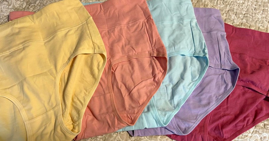 A collection of colorful underwear arranged in a row, featuring various pastel shades such as yellow, pink, light blue, lavender, and deep purple.