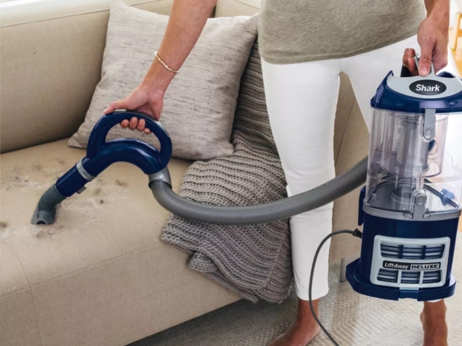woman cleaning a sofa with a Shark vacuum