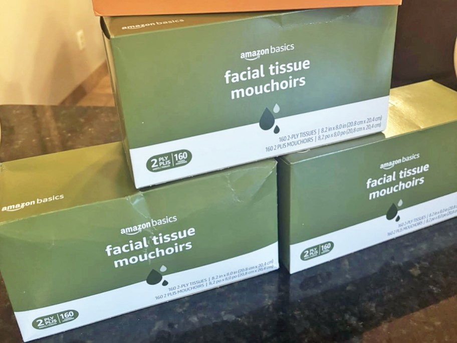 three green stacked boxes of Amazon Basics Facial Tissues