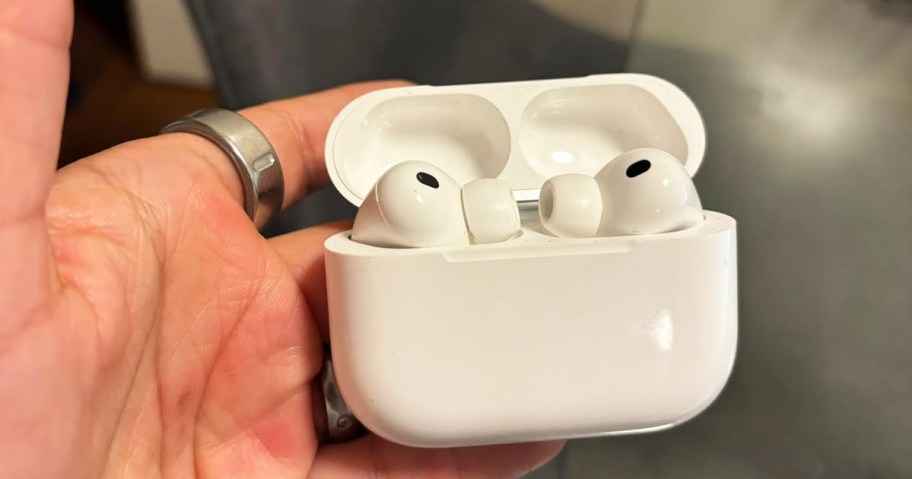 hand holding a pair of Apple AirPods Pro 3 in their charging case