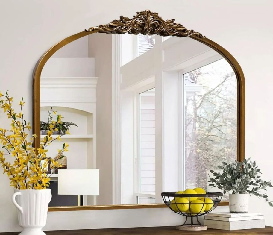 arched wooden wall mirror hanging above a console table