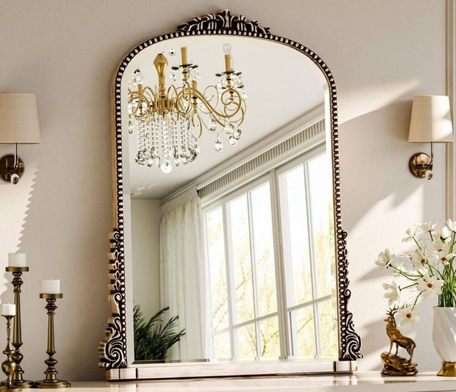 arched wall mirror hanging above a mantle