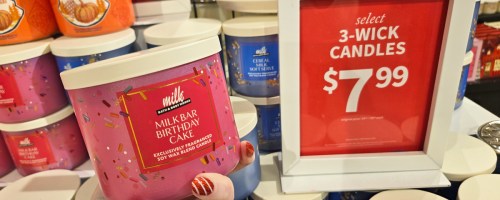 hand holding a 3-wick candle next to a $7.99 sale sign