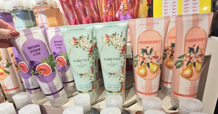 hand grabbing a tube of Bath & Body Works Body Cream from store display