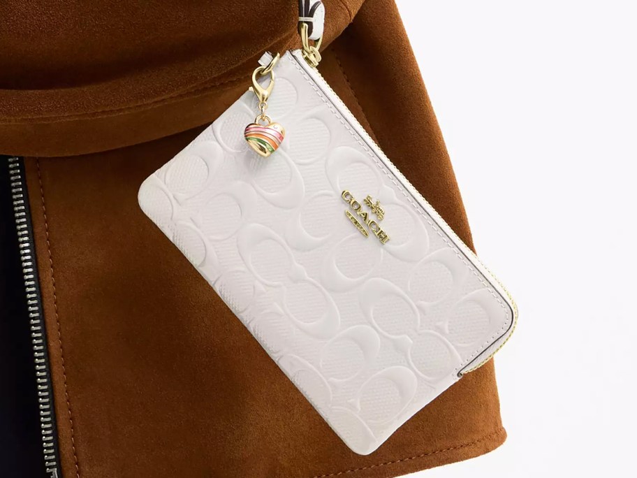 woman holding a white wristlet with a heart charm
