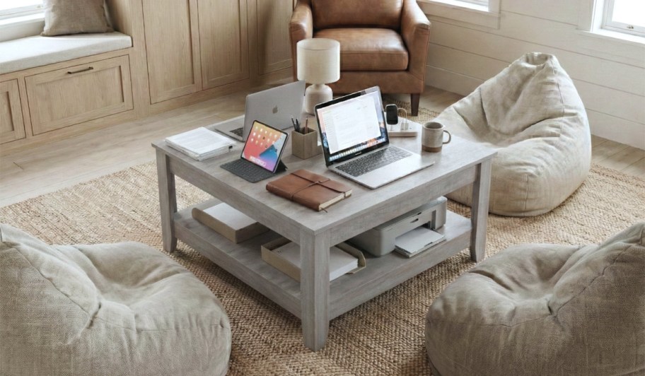 computer, laptop and accessories on a coffee table surrounded by bean bag chairs
