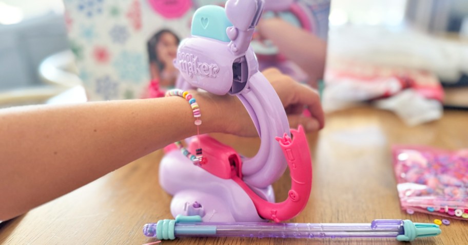 a girl's hand in a bracelet making kit machine