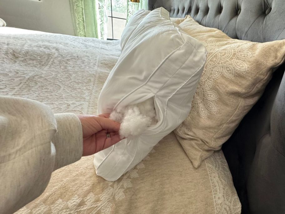 A bed with Coop pillows on it with the side unzipped showing the filling inside