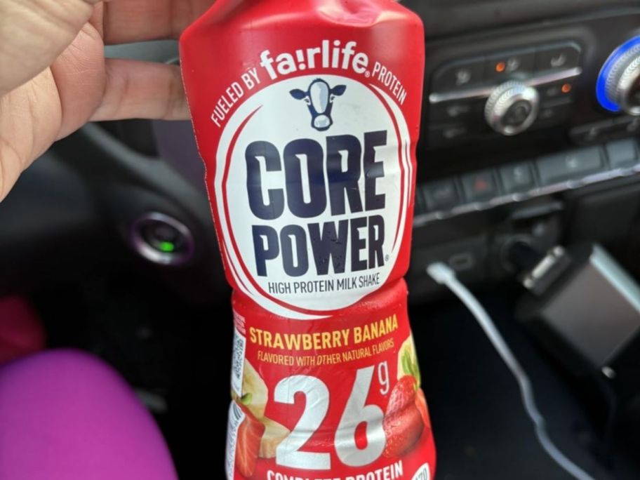 hand holding a Core power shake in strawberry at the car