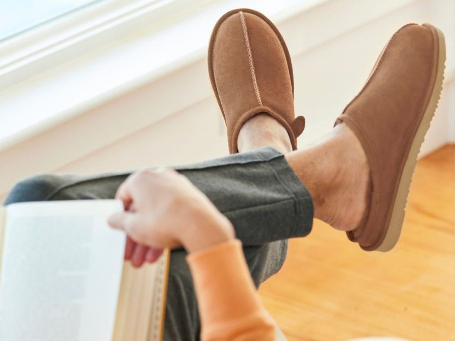 Man reading a book wearing Dearfoams Fireside Slippers