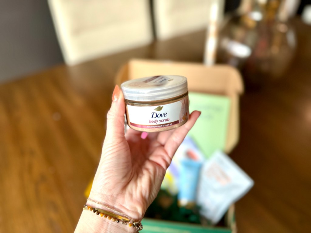 Woman holding up small bottle of dove body scrub
