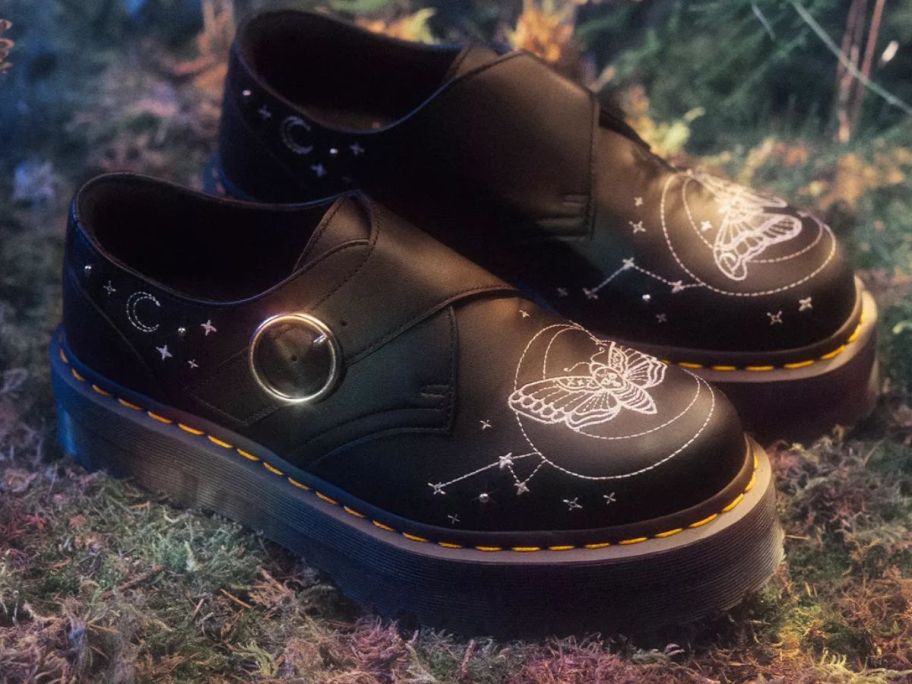 A pair of black shoes with butterflies on it 