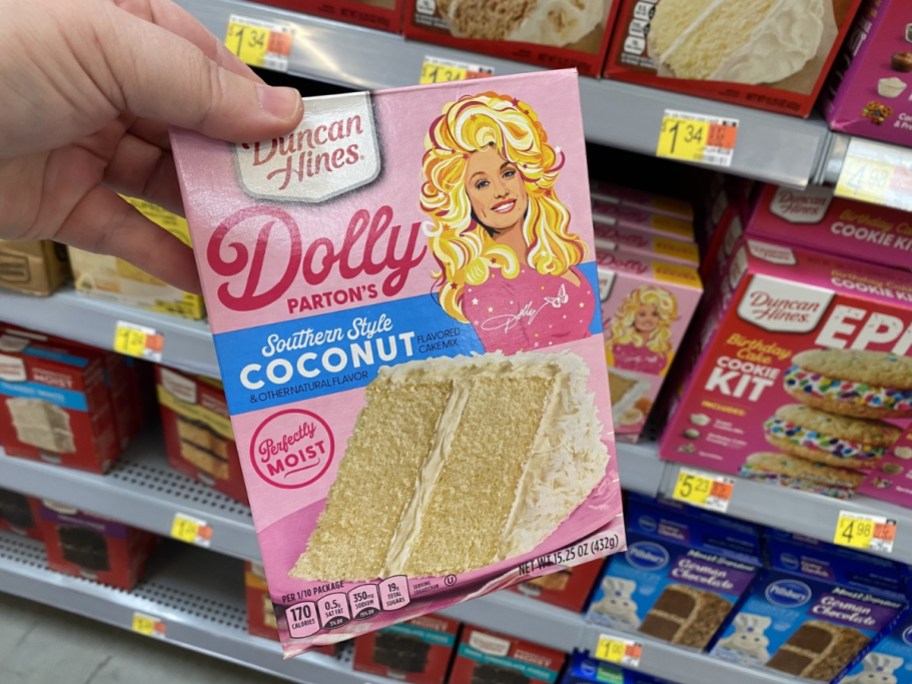 person holding box of duncan hines dolly parton coconut cake mix in store