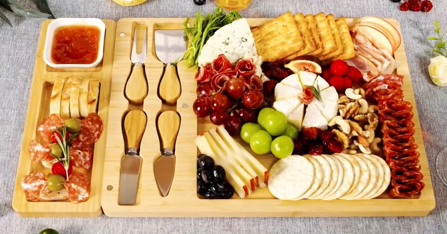 bamboo charcuterie board with cheeses, fruits, and crackers on it