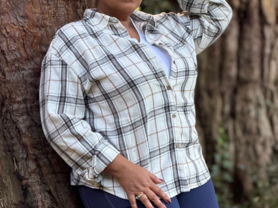 woman in plaid shirt leaning against tree