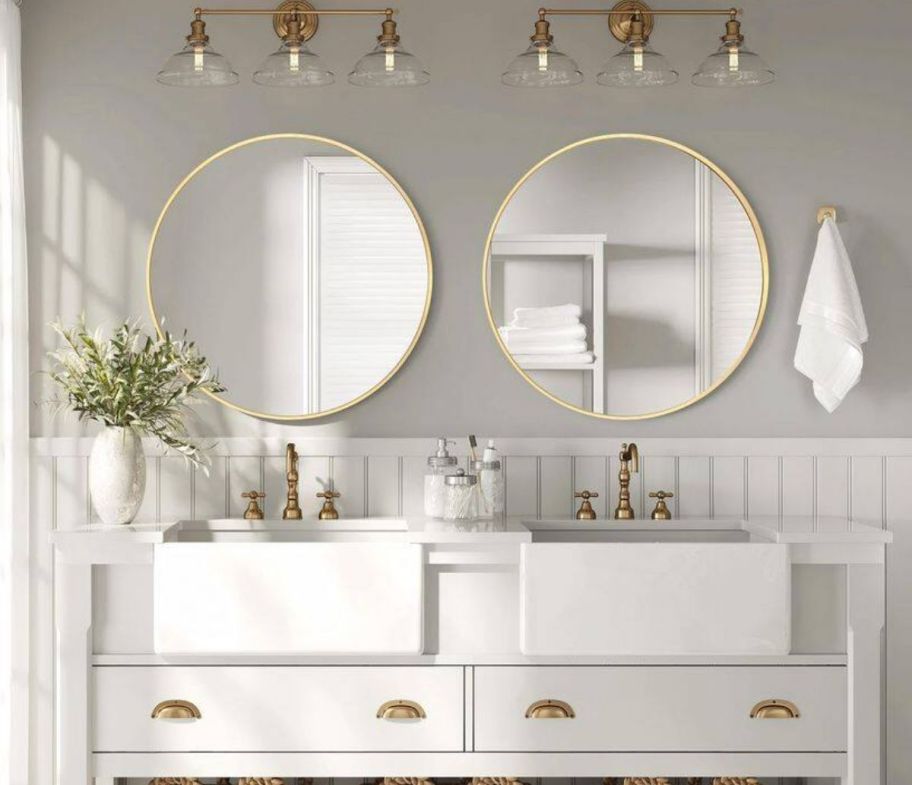 two round vanity mirrors hanging above a double sink