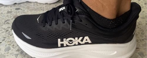 Someone wearing black Hoka shoes.