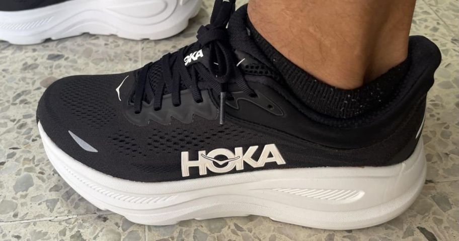 Someone wearing black Hoka shoes.