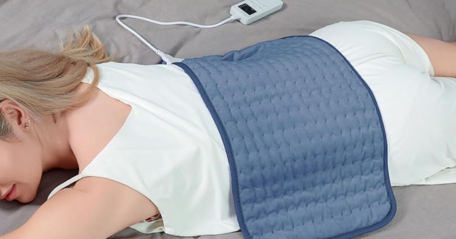 Woman laying down with a heating pad on her back