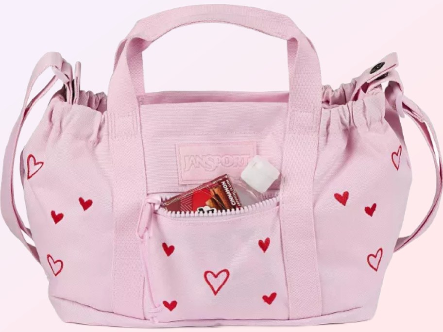 A pink JanSports bag wth red hearts.