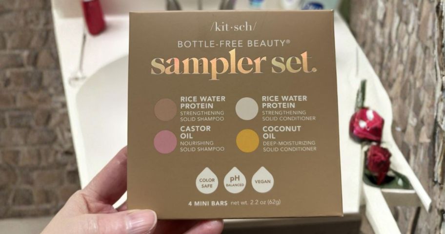 hand holding Kitsch Shampoo & Conditioner 4-Piece Sampler Set in bathroom