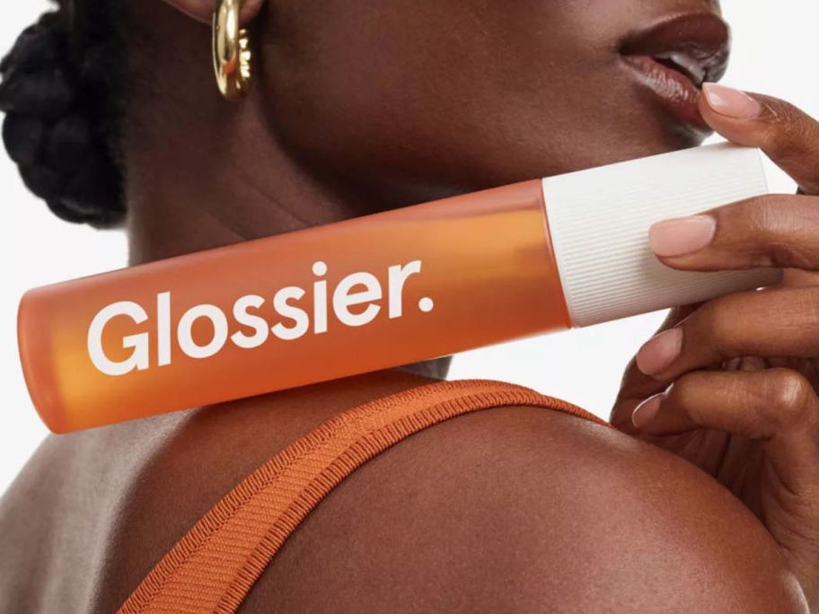 woman holding a Glossier body mist