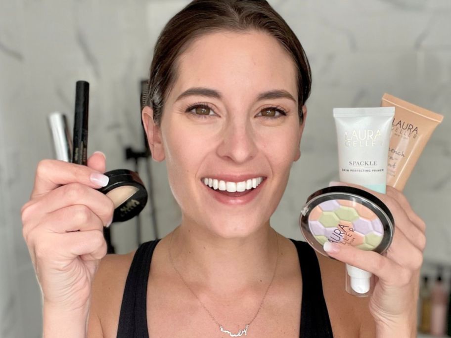 Woman holding several Laura Geller Makeup products