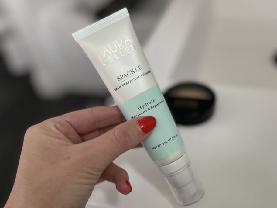 Hand holding a tube of Laura Geller Spackle