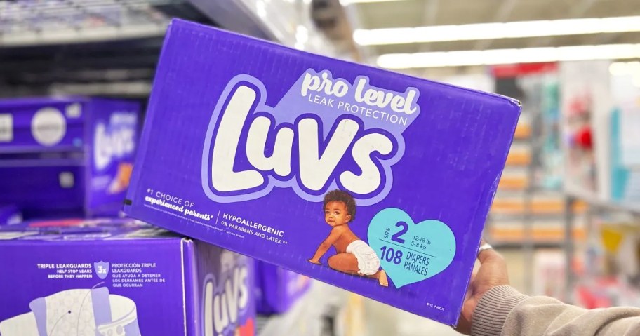 hand grabbing a purple box of Luvs diapers from store shelf