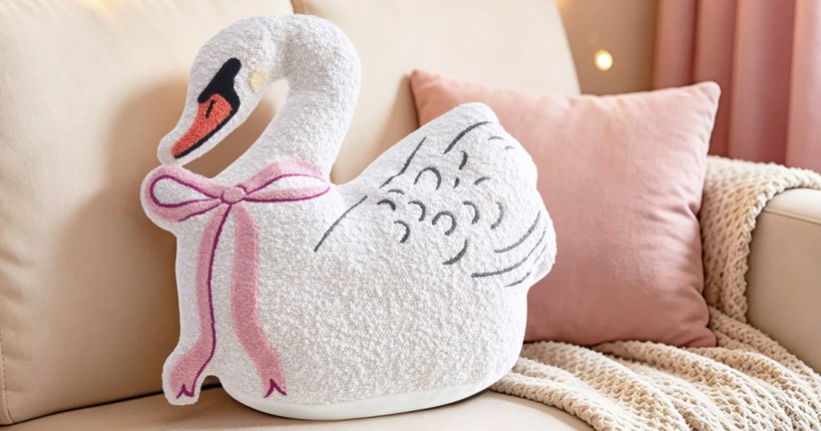 swan shaped throw pillow and a pink throw pillow on a couch