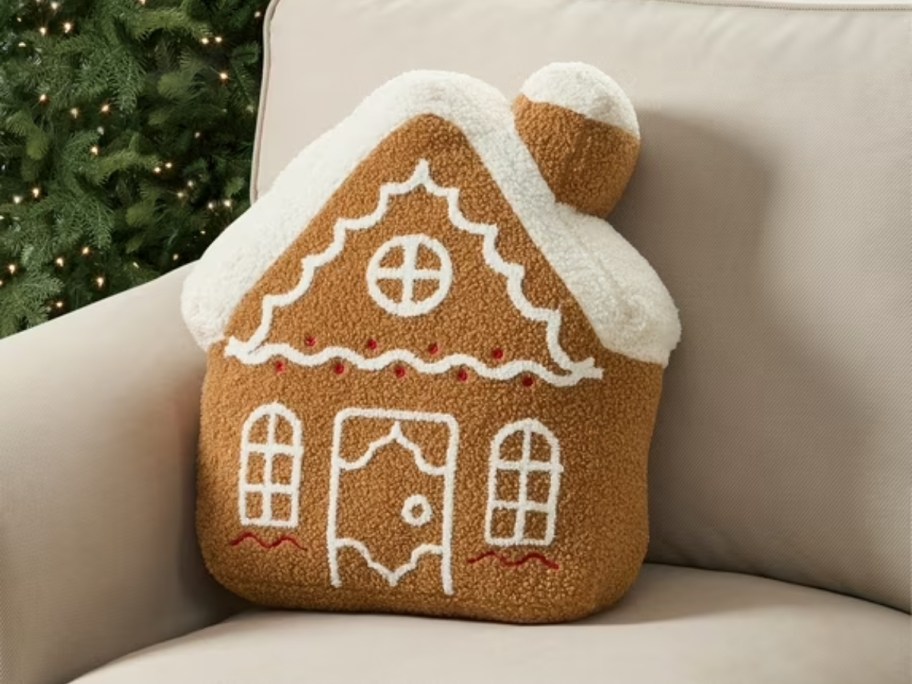 my texas house gingerbread house-shaped pillow sitting on beige couch