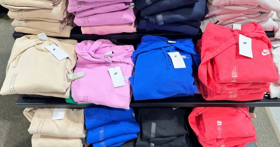 folded Nike hoodies on a table at a store