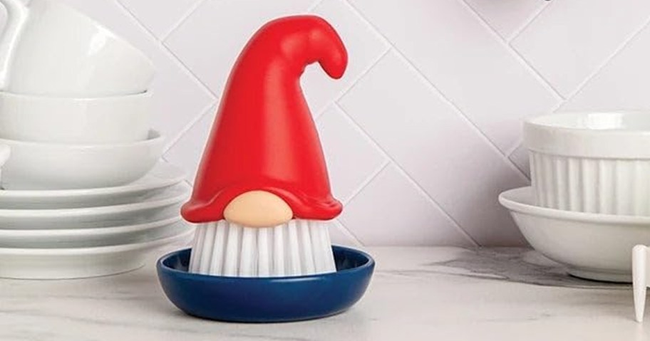 gnome shaped dish brush near stack of dishes