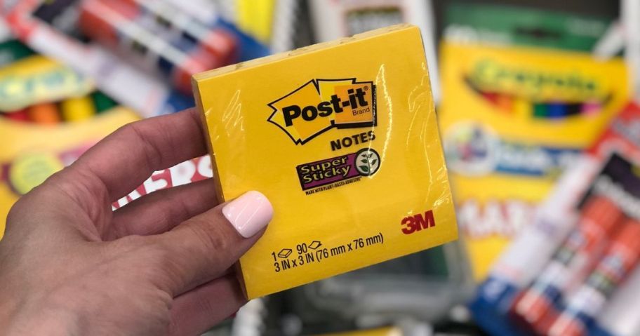 Hand holding a pack of yellow post-it notes
