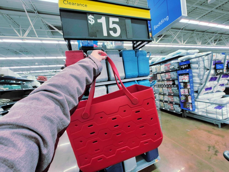 Woman in Walmart store holding up red plastic bag in front of $15 clearance sign