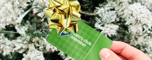 hand holding a sams club membership card with a gold bow on it