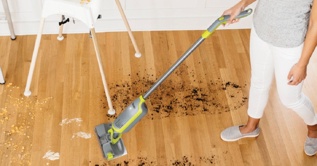Woman using shark vac mop to clean wooden floor in kitchen